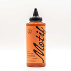 Bottle of Motif Premium Cinnamon Babka Syrup with an orange label and black twist precision cap.