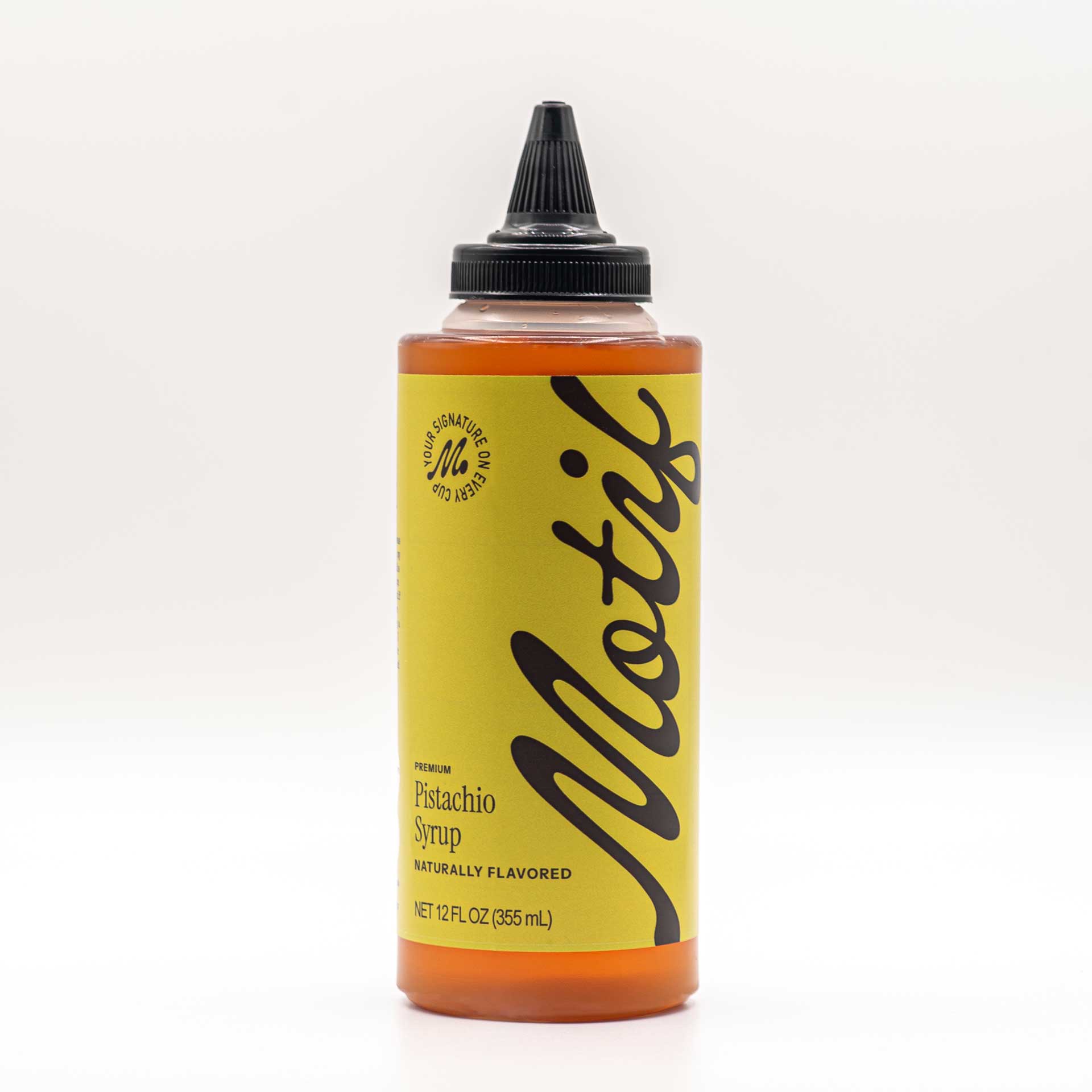 Bottle of Motif Premium Pistachio Syrup with a pistachio green label and black twist precision cap.