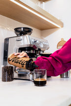 Woman in a magenta sweater pouring Chocolate Syrup into a glass mug using the bottle's precision cap.