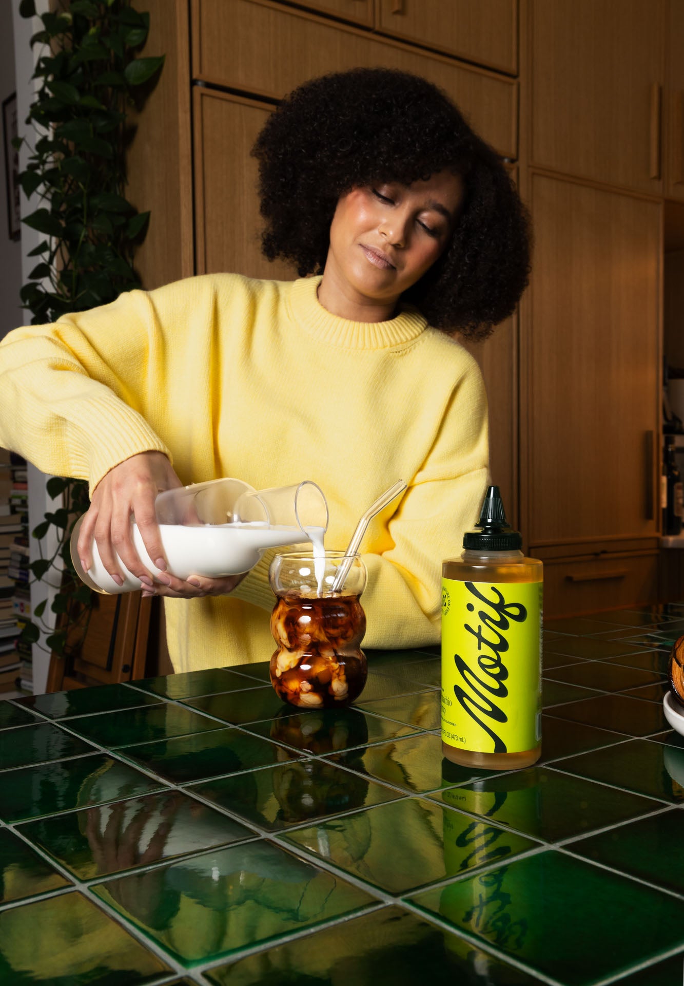 Pouring milk into a glass of iced coffee and Pistachio Syrup.