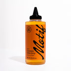 Bottle of Motif Premium Cinnamon Babka Syrup with an orange label and black twist precision cap.