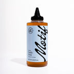 Bottle of Motif Premium Vanilla Syrup with a light blue label and black twist precision cap.